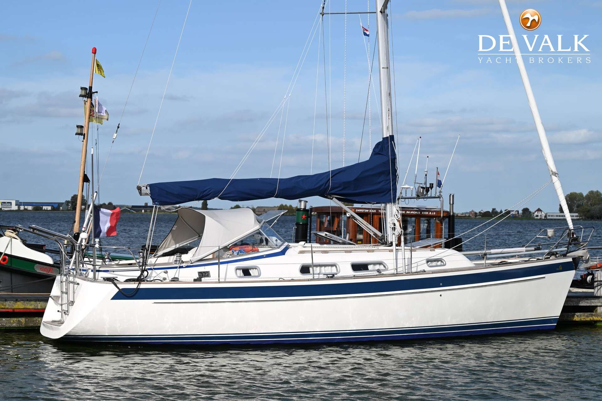 Hallberg-Rassy 342 2009 Hallberg-Rassy 342 sailboat docked, featuring blue and white design, with flags and calm waters.
