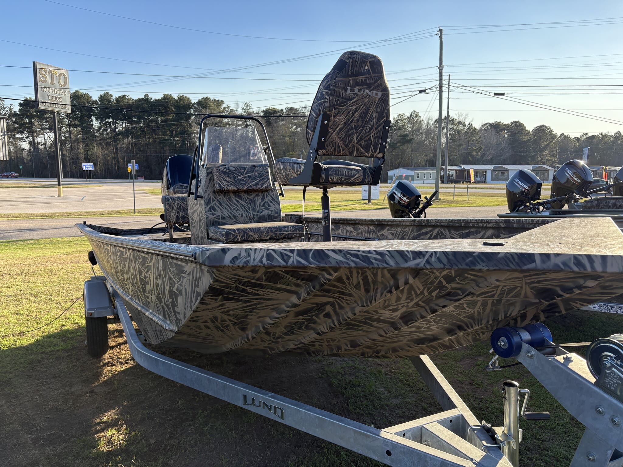 Lund 1870 Predator CC 2024 Lund 1870 Predator CC boat with camouflage design on a trailer, parked outdoors.