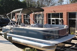 Tahoe Pontoon LTZ Elite 2026 Tahoe Pontoon LTZ Elite boat with canopy, docked near a brick building.