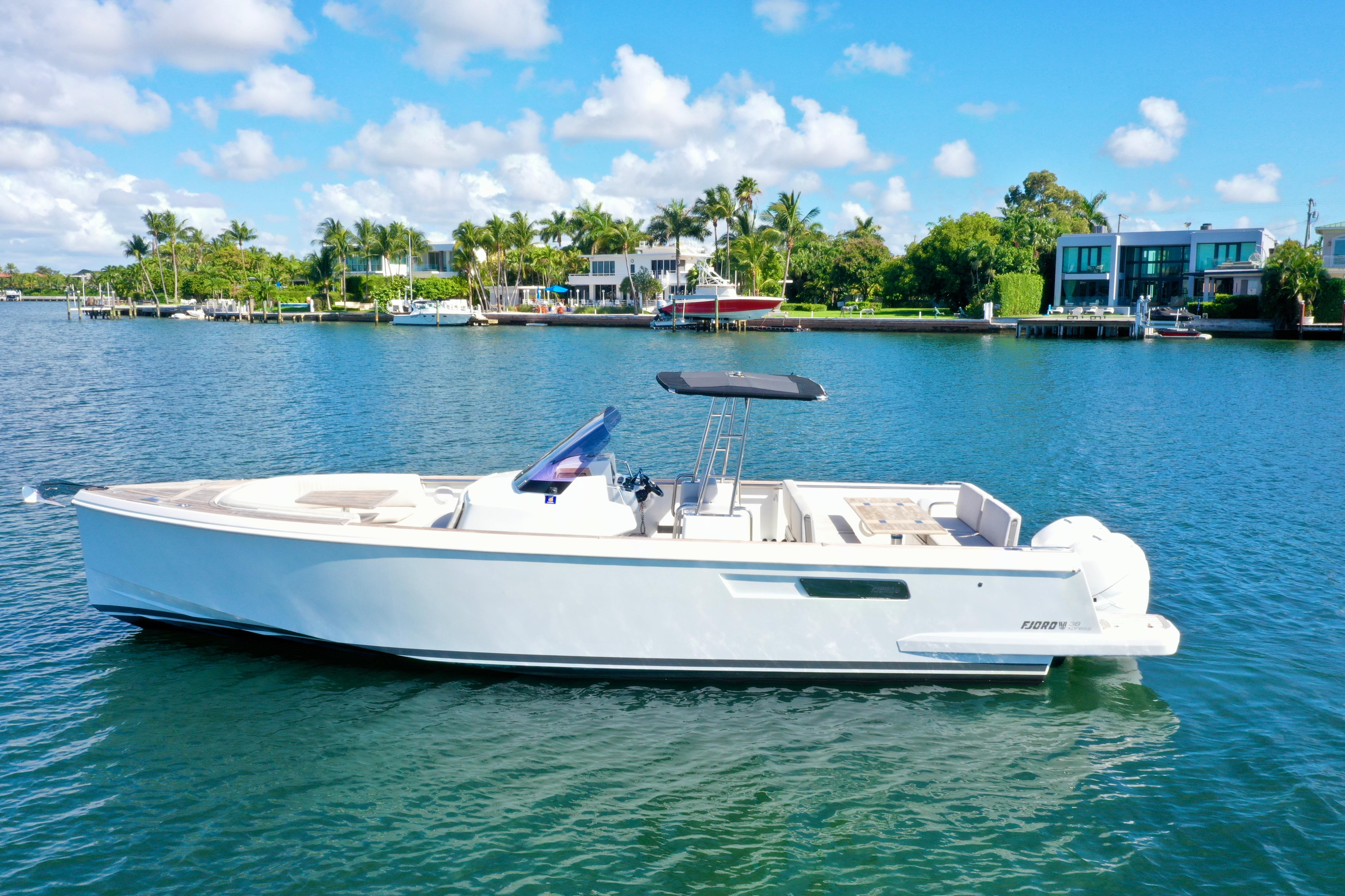 Fjord 38 Xpress 2019 Fjord 36' Open boat on a sunny waterfront with palm trees and luxury homes.