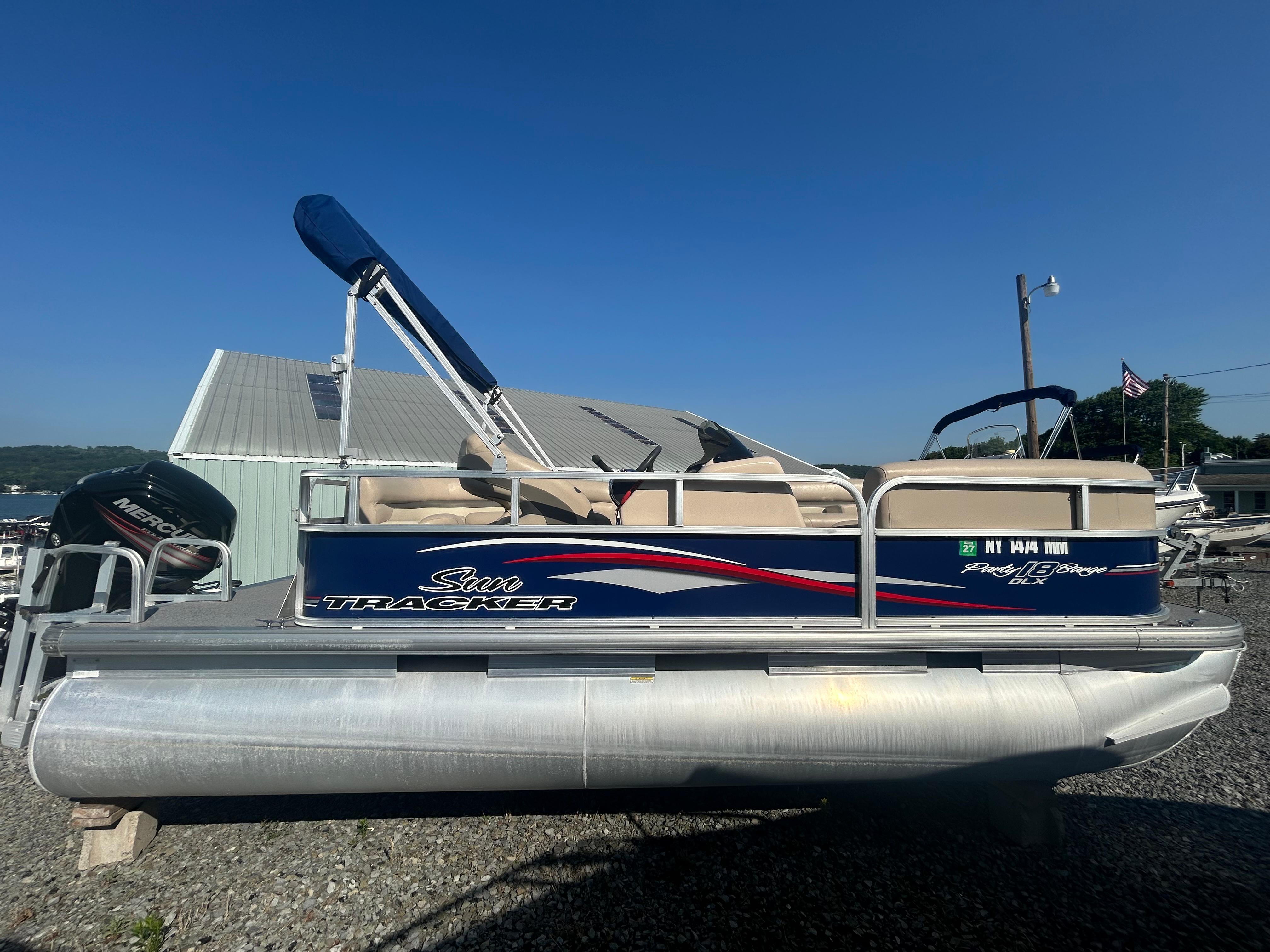 Sun Tracker Party Barge 18 DLX 2016 Sun Tracker Party Barge 18 DLX pontoon boat with canopy, parked on gravel.
