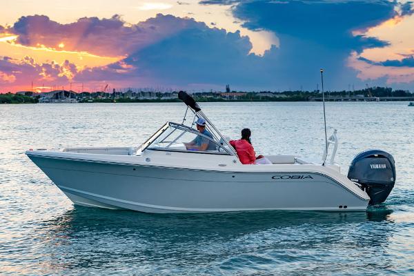 Cobia 220 Dual Console 2025 Cobia 220 Dual Console boat cruising at sunset on calm waters.