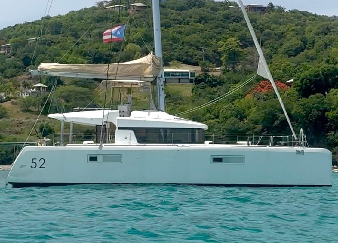 Lagoon 52 F Lagoon 52 F catamaran from 2015, anchored near lush green hills.