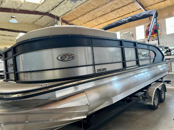 Manitou 23 Encore SR 2022 Manitou 23 Encore SR pontoon boat on a trailer in an indoor showroom.
