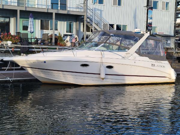 Larson 290 CABRIO 1997 Larson 290 CABRIO boat docked at marina, white exterior, calm water reflection.