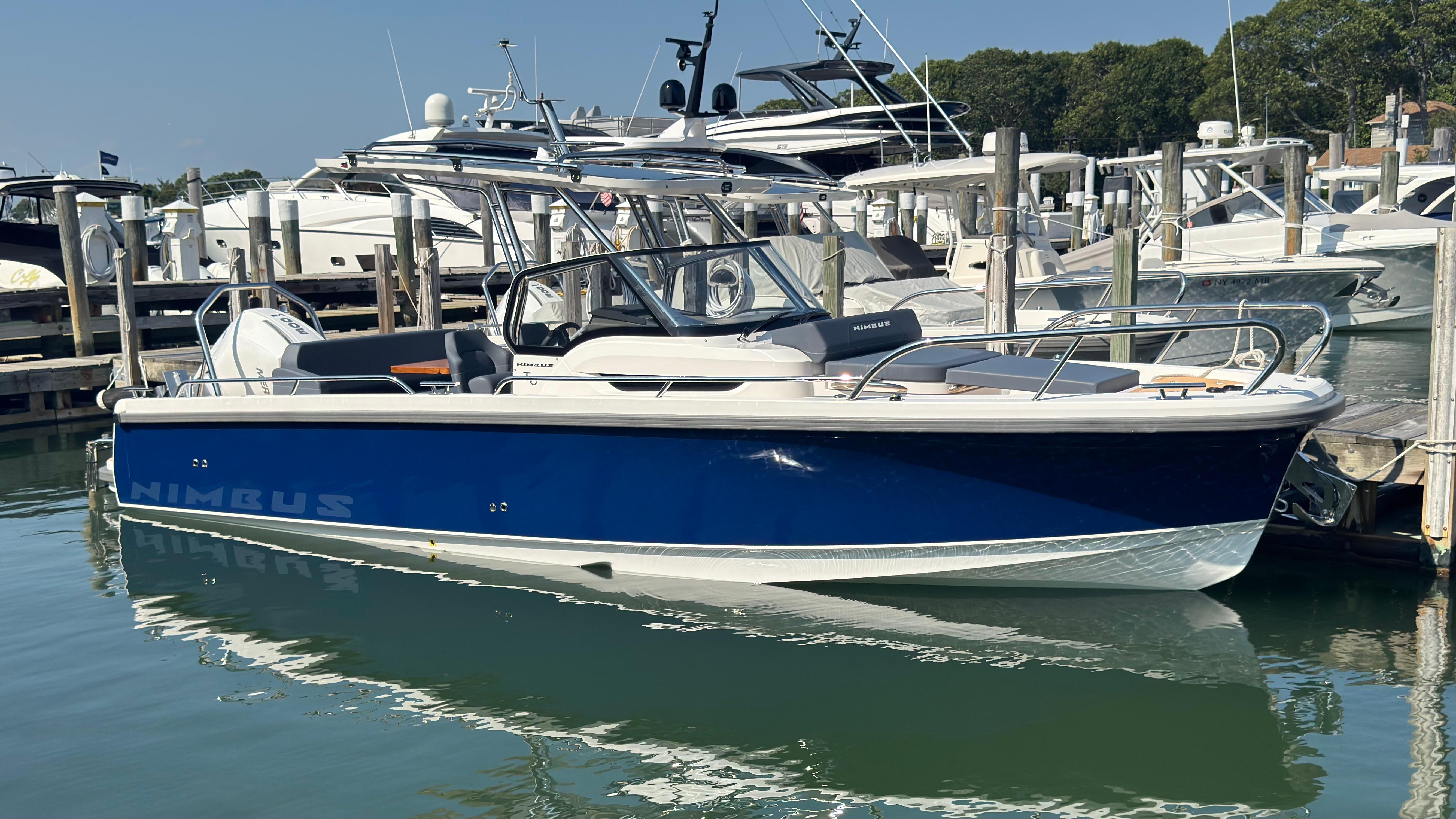 Nimbus T8 2024 Nimbus T8 boat docked at marina, featuring sleek blue and white design.