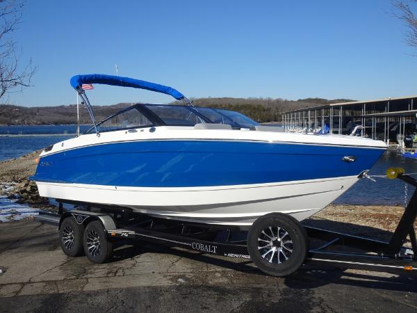 Cobalt R4 2025 Cobalt R4 boat on trailer by a lake, featuring a blue and white design.