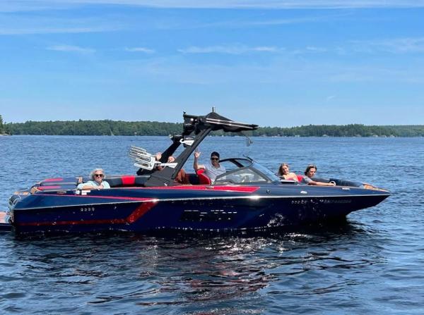 Malibu Wakesetter 24 MXZ 2021 Malibu Wakesetter 24 MXZ on a lake with passengers enjoying a sunny day.