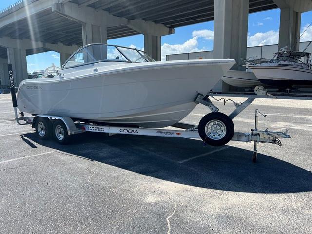 Cobia 220 DC 2024 Cobia 220 DC boat on trailer under bridge, sunny day.