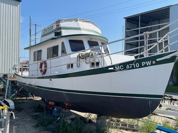 Maritime 340 Trawler 1989 Maritime 340 Trawler boat on dry dock, white with green accents, side view.