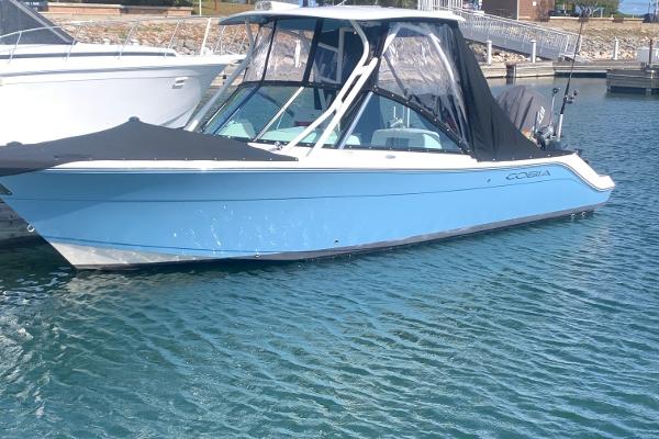 Cobia 240 DC 2022 Cobia 240 DC boat with black canopy docked in marina.