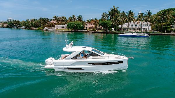 Jeanneau DB 37 2024 Jeanneau DB 37 OB cruising on a tropical waterway with palm trees in the background.