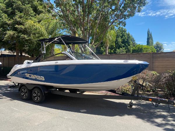 Scarab 235 SE 2025 Scarab 235 SE boat on trailer, blue and white design, parked outdoors.