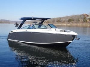 Cobalt R33 Surf 2025 Cobalt R33 Surf boat cruising on a calm lake under clear skies.