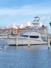Hatteras 54 Convertible 2006 Hatteras 54 Convertible yacht docked in a marina with colorful buildings in the background.
