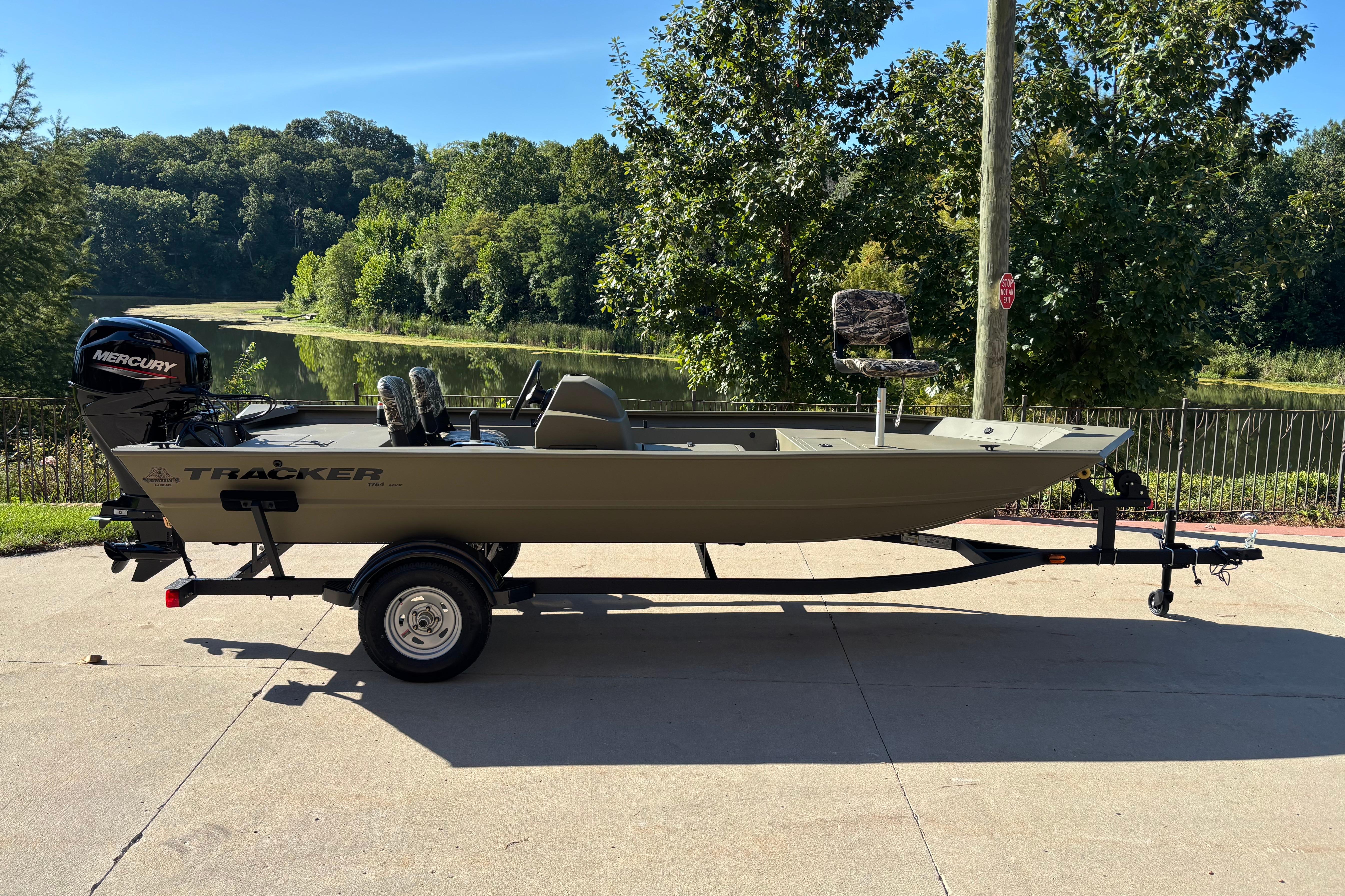 Tracker Grizzly 1754 SC 2026 Tracker Grizzly 1754 SC boat on trailer, parked near scenic lake.