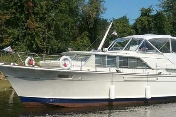 Chris-Craft 42 Commander 1970 Chris-Craft 42 Commander yacht on calm water, surrounded by lush greenery.