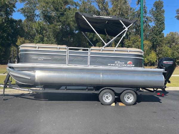 Sun Tracker Party Barge 20 DLX 2025 Sun Tracker Party Barge 20 DLX pontoon boat on trailer, parked outdoors.