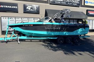 MasterCraft X26 2021 MasterCraft X26 boat on trailer outside dealership, vibrant turquoise and black design.