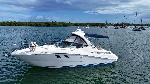 Sea Ray 310 Sundancer 2009 Sea Ray 310 Sundancer yacht on calm water with sailboats in the background.
