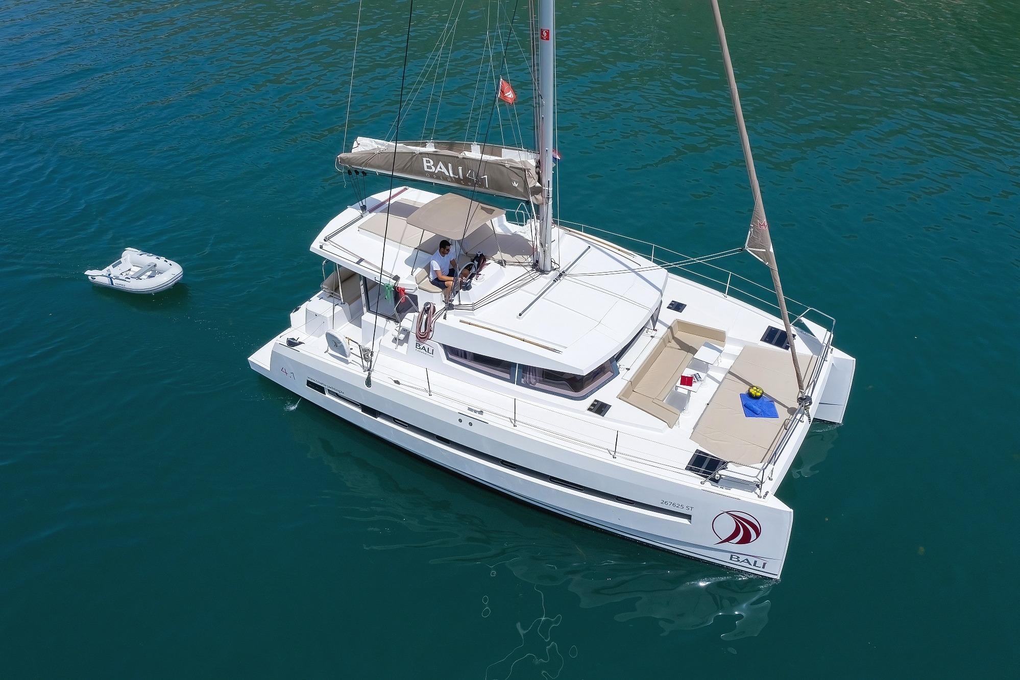 Bali 4.1 2020 Bali 4.1 catamaran sailing on clear blue water with a small dinghy nearby.