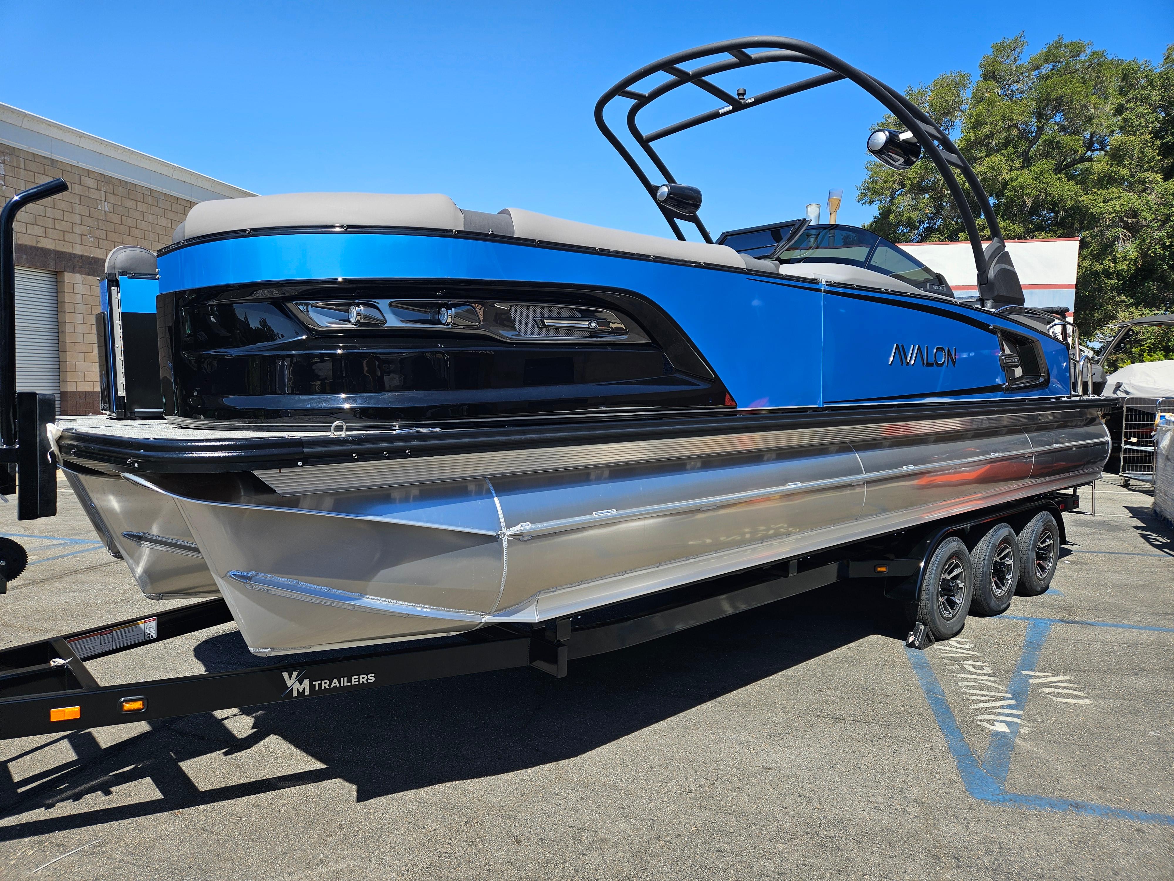 Avalon Excalibur LTD Elite Windshield 27FT 2025 Avalon Excalibur LTD Elite Windshield 27FT boat on trailer, blue and black design.