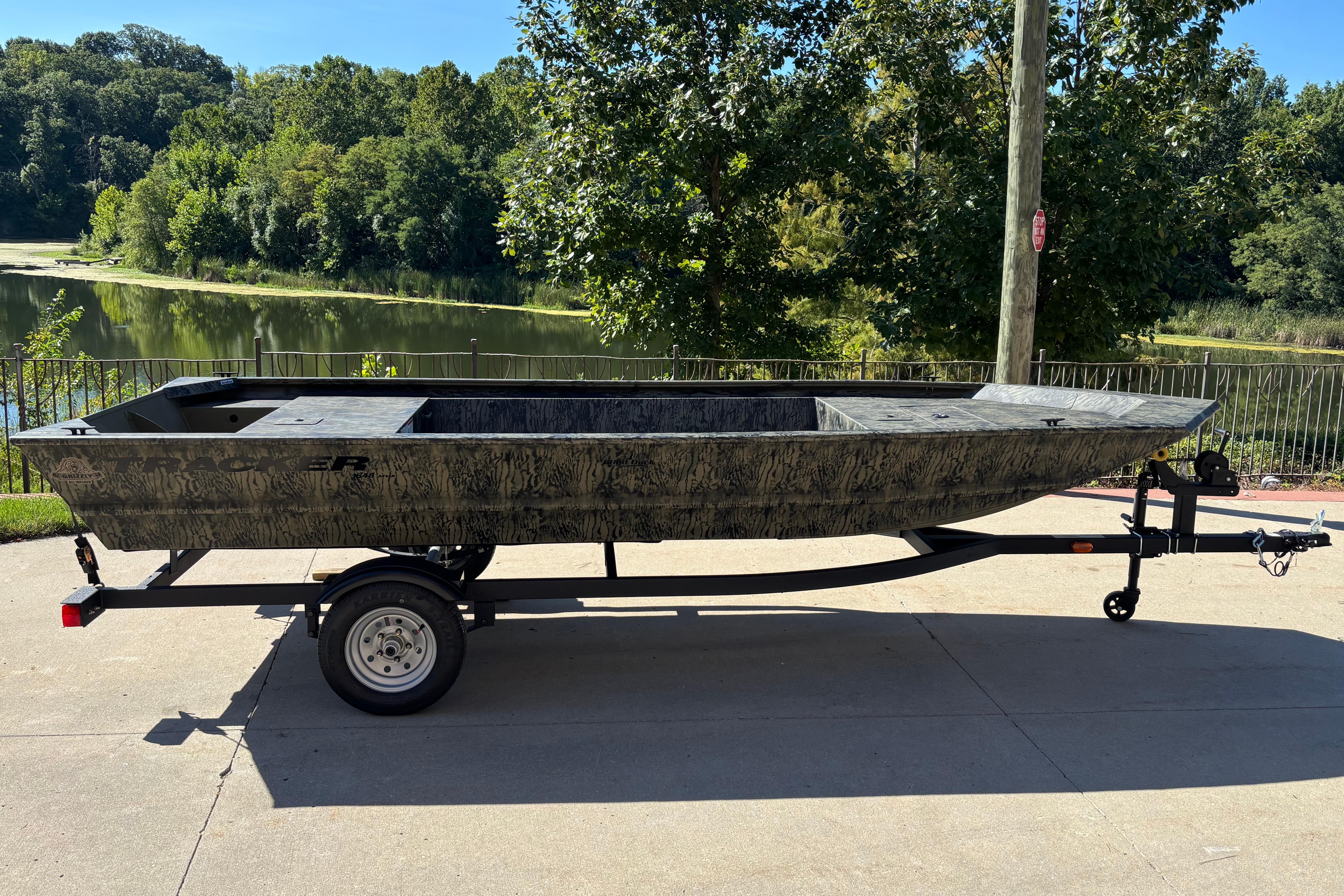 Tracker Grizzly 1648 Utility 2026 Tracker Grizzly 1648 Utility boat on trailer, parked near a scenic lake.