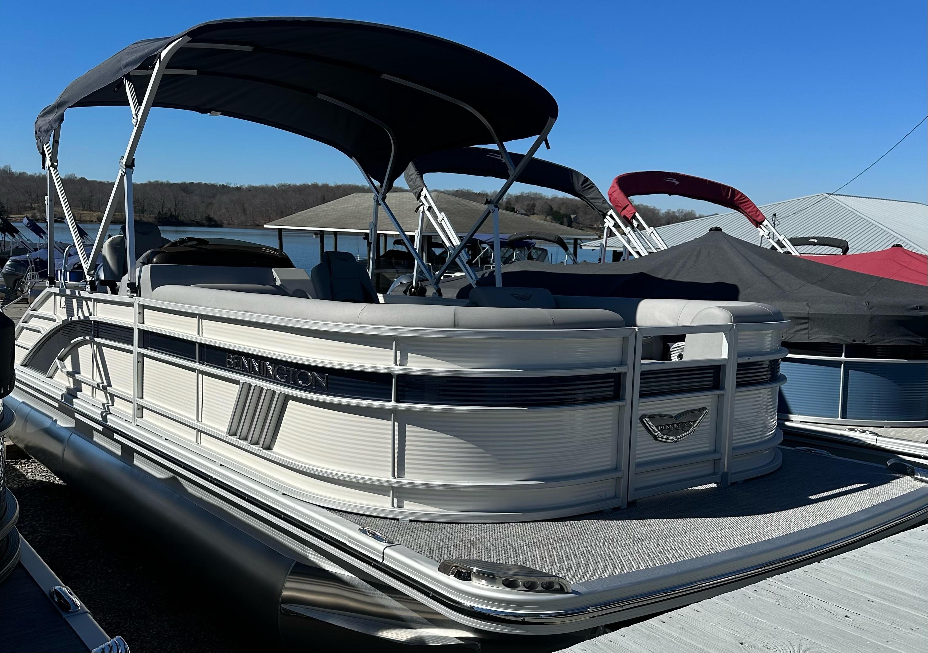 Bennington L 23 Swingback 2024 Bennington L 23 Swingback pontoon boat with canopy, docked under clear blue sky.