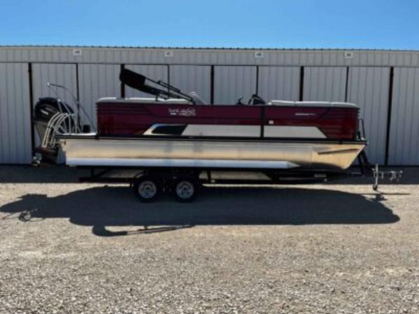 SunCatcher Elite 324 RC 2025 SunCatcher Elite 324 RC pontoon boat on trailer, parked outside storage facility.