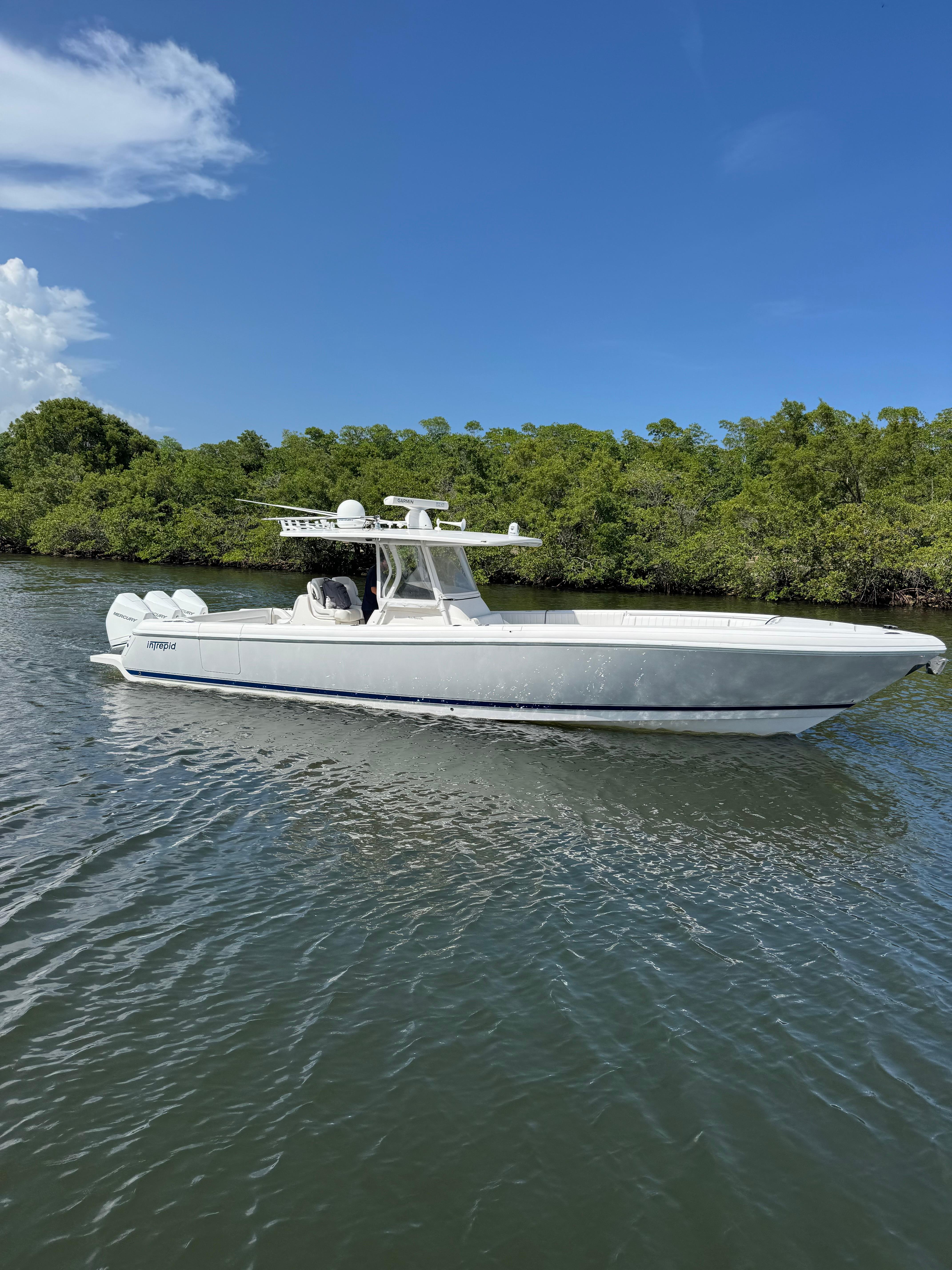 Intrepid 375 Center Console 2015 Intrepid 375 Center Console boat cruising on a sunny day near lush greenery.