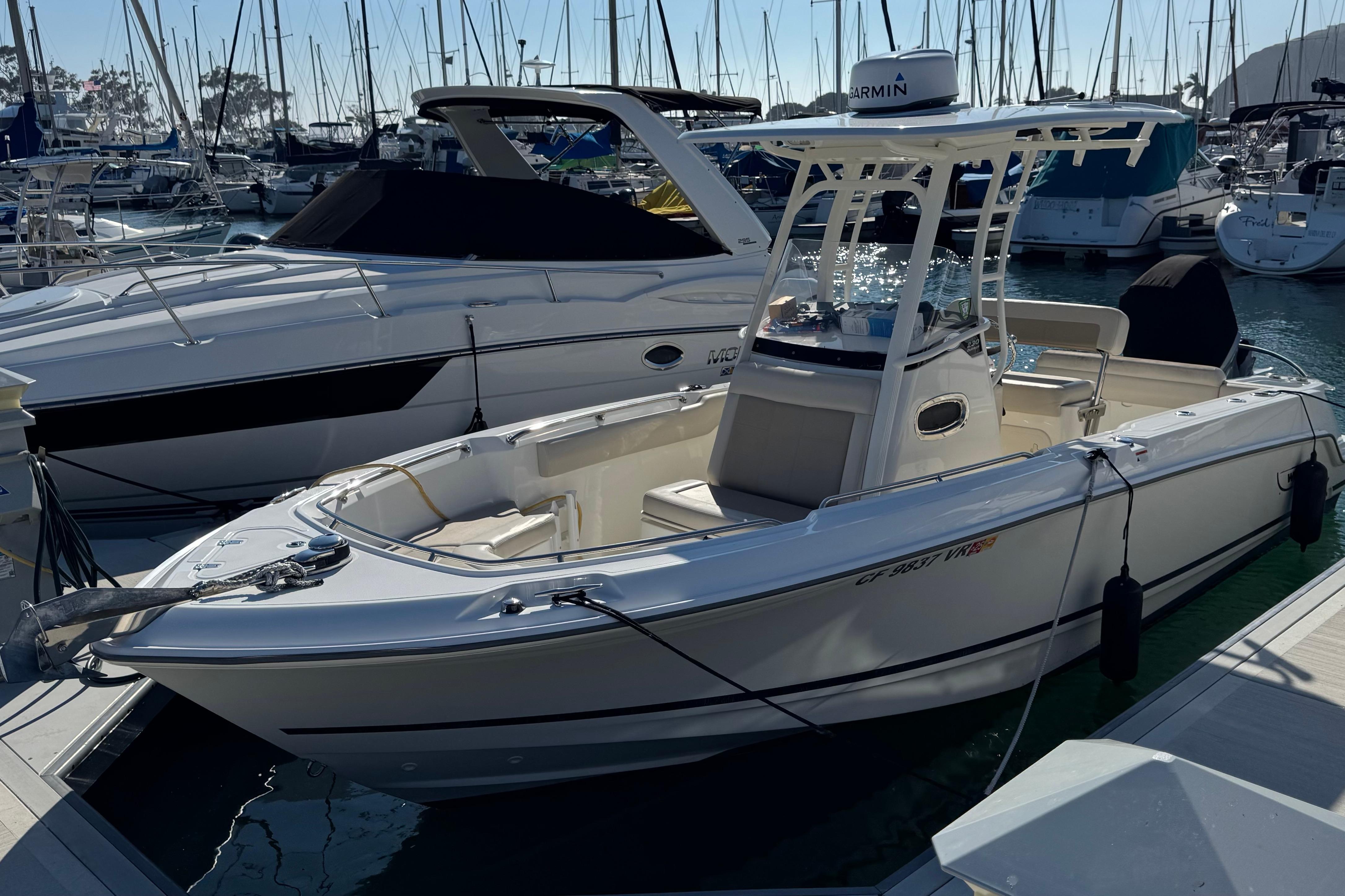 Boston Whaler 230 Outrage 2019 Boston Whaler 230 Outrage boat docked in a marina, surrounded by other vessels.