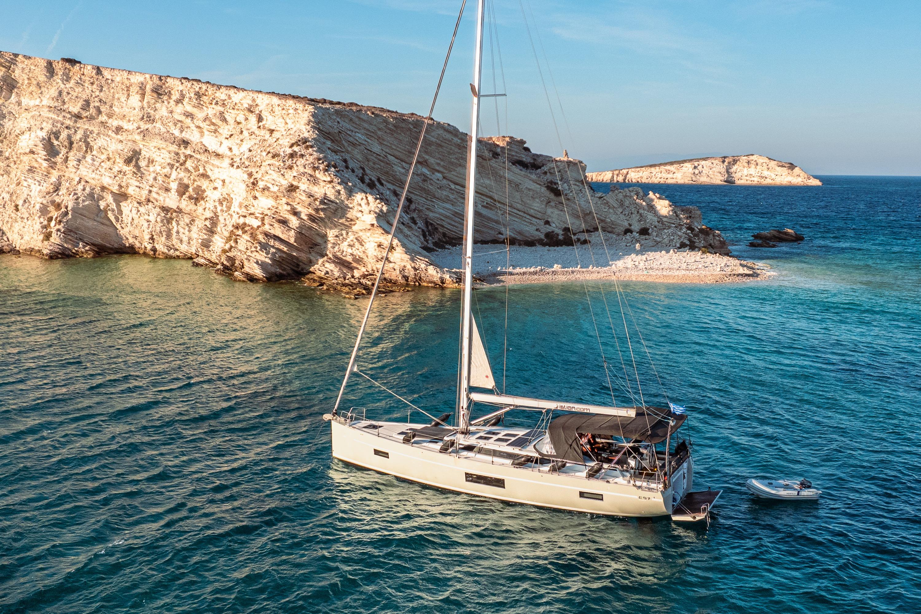 Bavaria C57 Sailing yacht Bavaria C57 (2022) anchored near rocky coastline in clear blue waters.