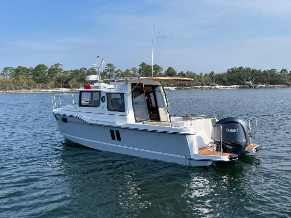 Ranger Tugs R-25 2025 Ranger Tugs R-25 boat on calm water with Yamaha outboard motor.