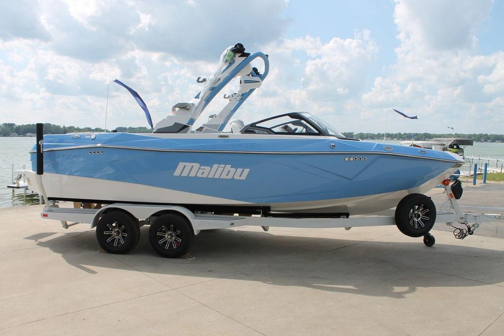 Malibu Wakesetter 23 LSV 2026 Malibu 23 LSV boat in blue on trailer by a lake.