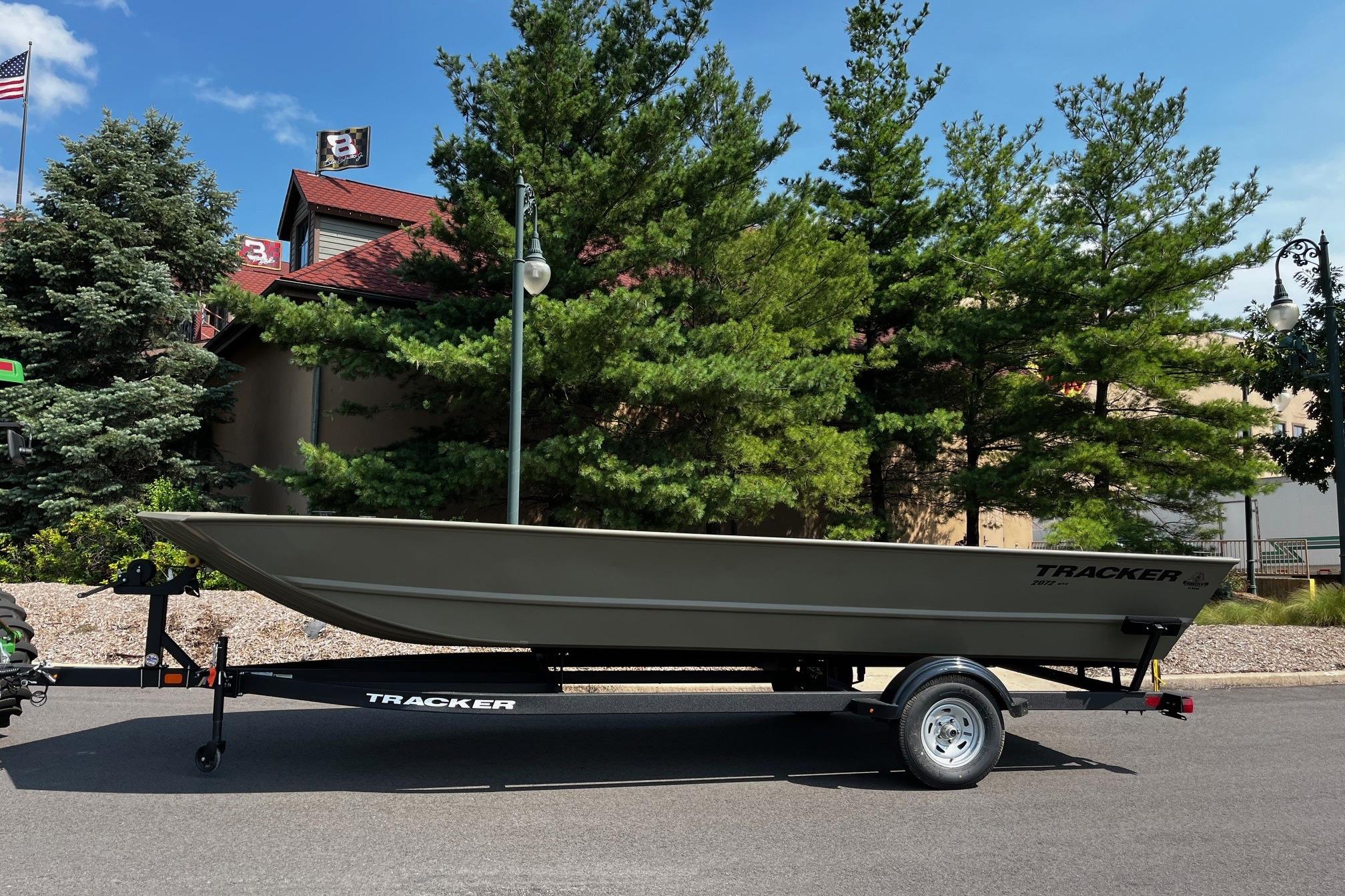 Tracker GRIZZLY 2072 Utility 2026 Tracker GRIZZLY 2072 Utility boat on trailer, parked near trees and building.