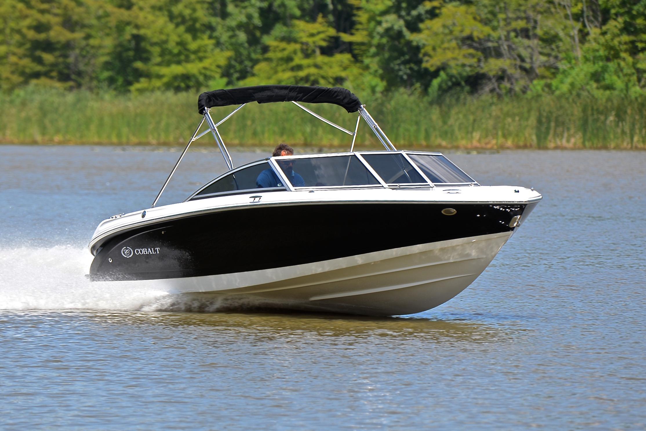 Cobalt 200 2011 Cobalt 200 boat cruising on a lake with lush green trees in the background.