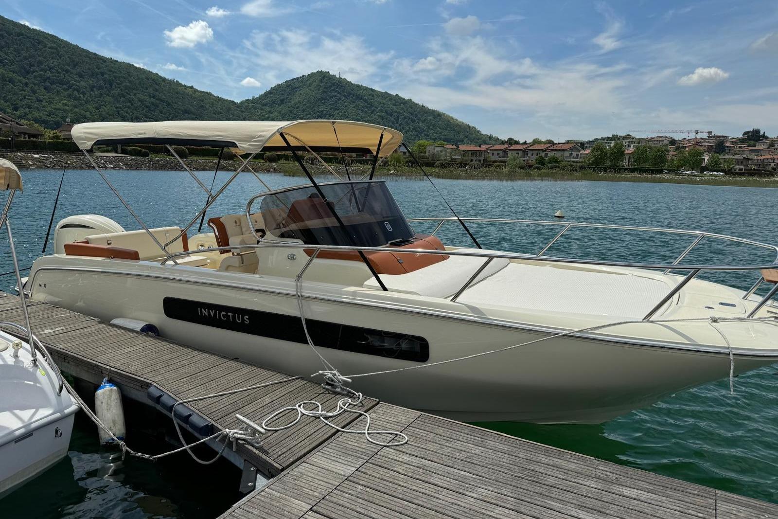 Invictus Capoforte CX 270 2022 Invictus Capoforte CX 270 boat docked on a scenic lake with mountains.