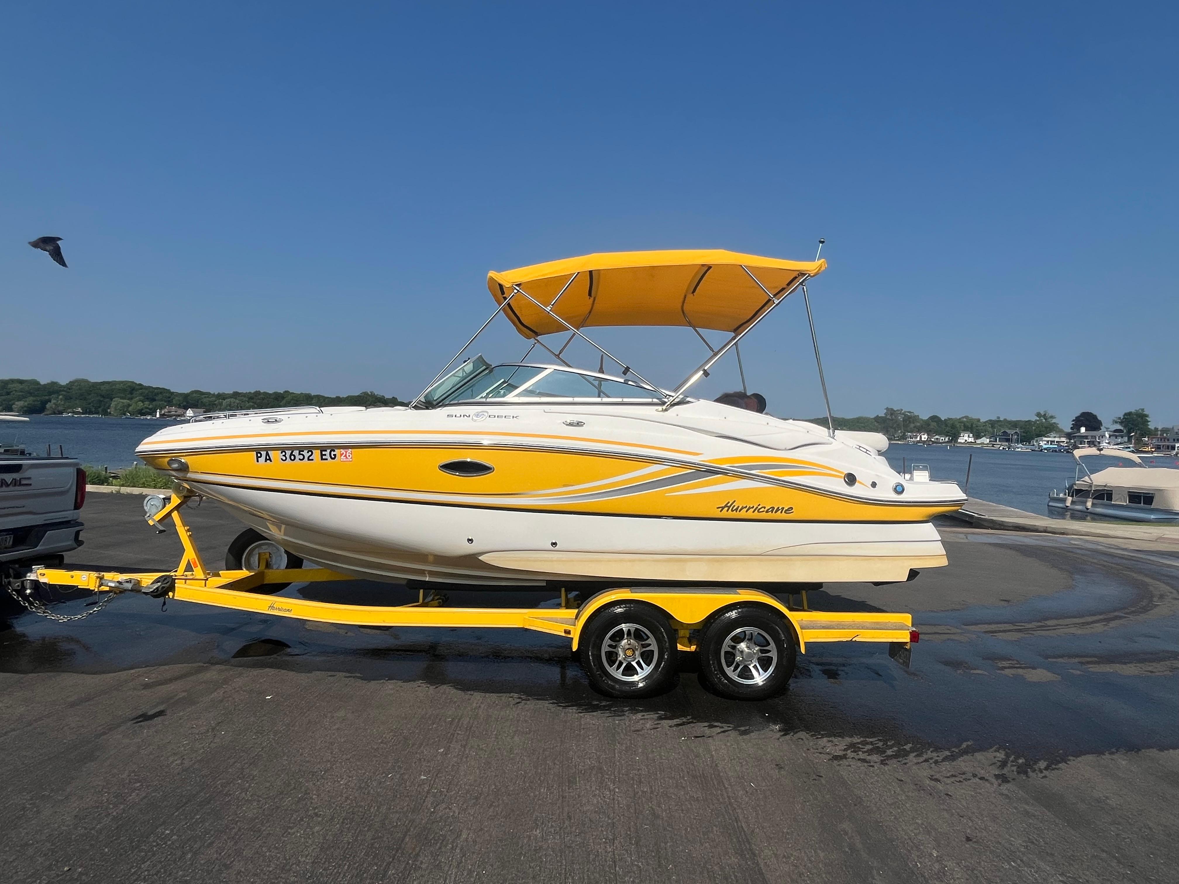 Hurricane SunDeck 2200 DC IO 2013 Hurricane SunDeck 2200 DC IO boat on trailer by waterfront, yellow and white design.