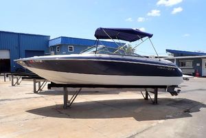 Cobalt 240 2002 Cobalt 240 boat with blue canopy on a stand at a marina.