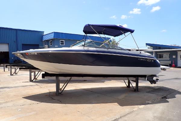 Cobalt 240 2002 Cobalt 240 boat with blue canopy on a stand at a marina.