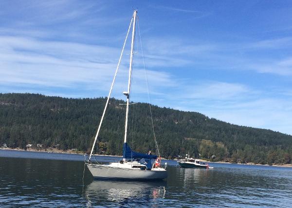 C&C MK II Sailboat on calm water, C&C MK II 1986, with forested hills in the background.