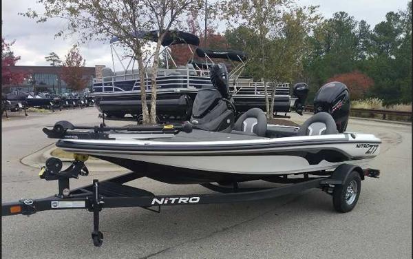 Nitro Z17 2025 Nitro Z17 boat on trailer in parking lot, surrounded by trees and other boats.