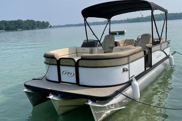 Manitou Aurora LE RF VP 2021 Manitou Aurora LE RF VP pontoon boat on a serene lake.