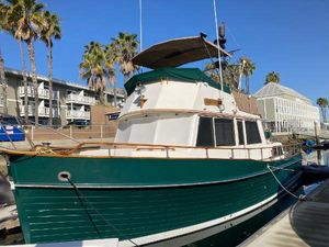 Grand Banks 42 Classic 1985 Grand Banks 42 Classic yacht docked, featuring green hull and white cabin, with palm trees nearby.