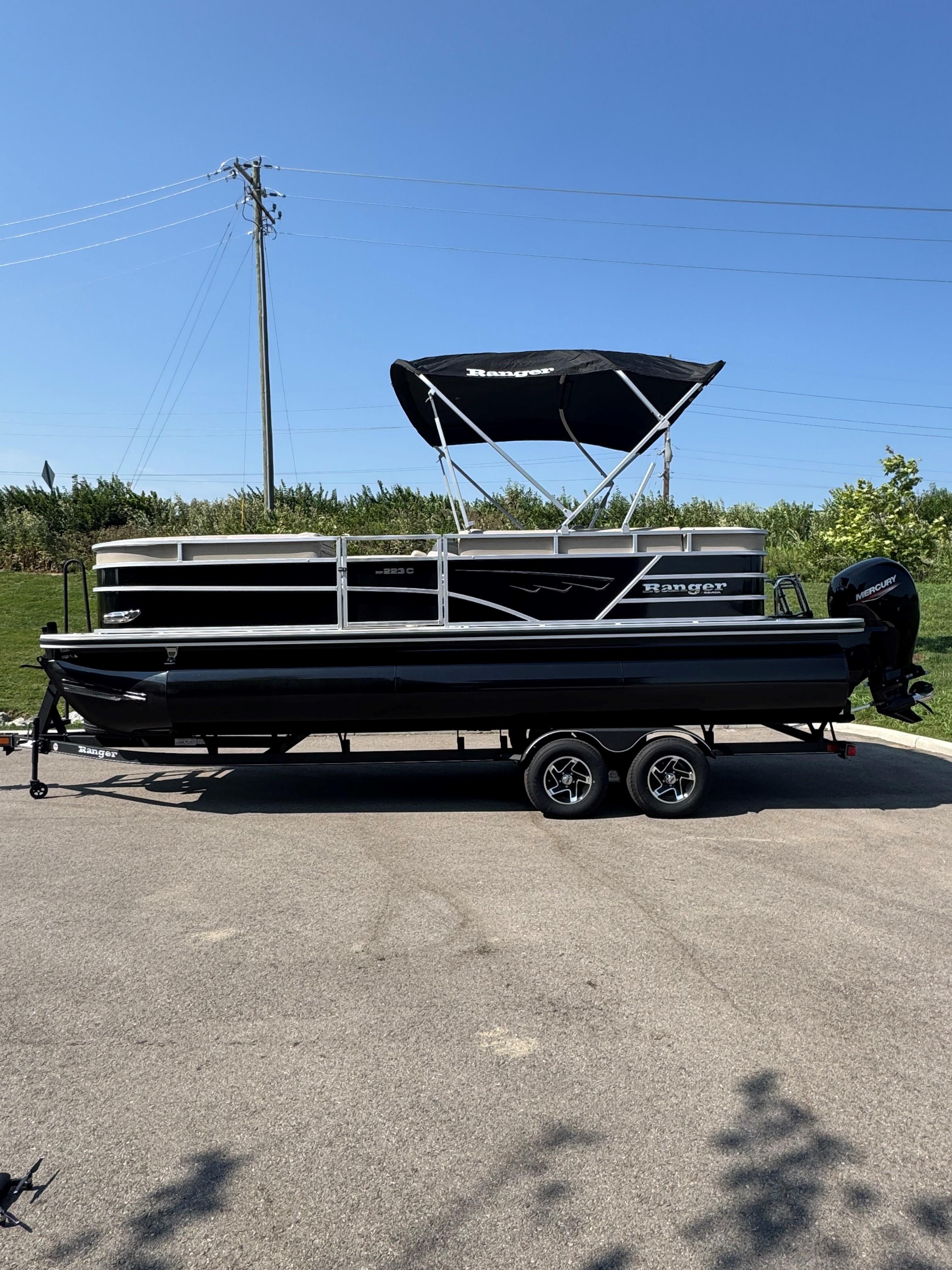 Ranger Reata 223C 2024 Ranger Reata 223C pontoon boat on trailer under clear blue sky.