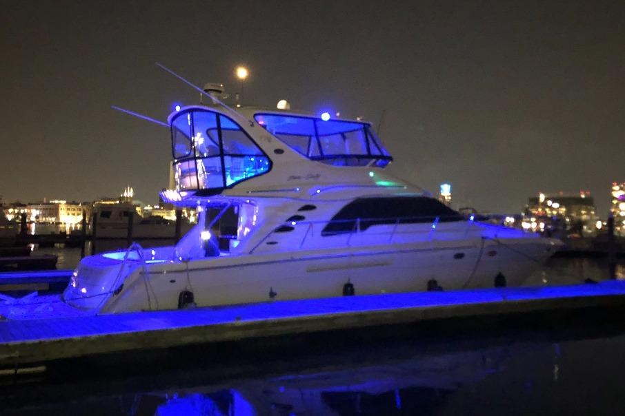 Sea Ray 560 Sedan Bridge 2002 Sea Ray 550 Sedan Bridge yacht illuminated with blue lights at night in a marina.