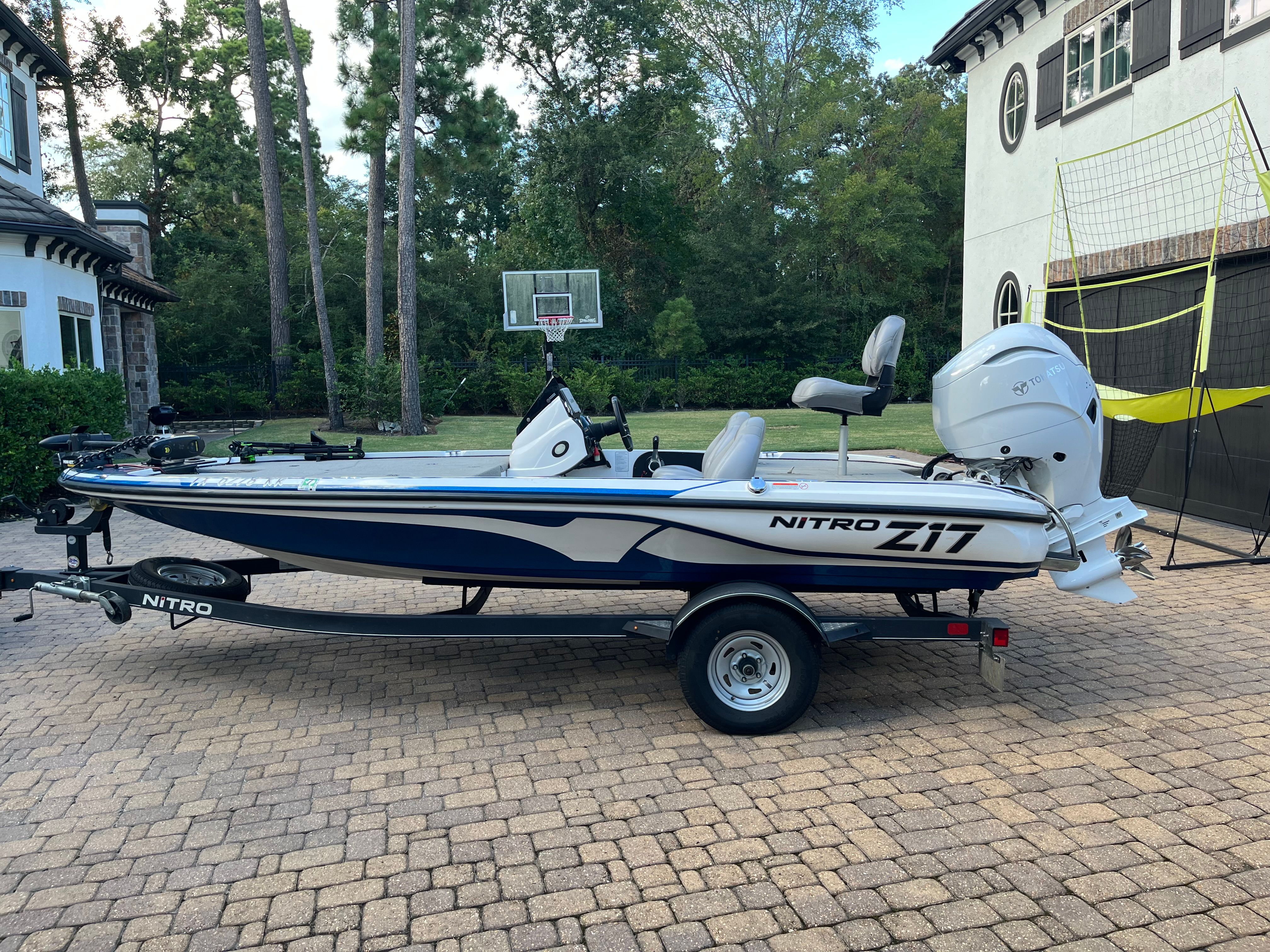 Nitro Z17 2018 Nitro Z17 boat on trailer in driveway, surrounded by trees and houses.