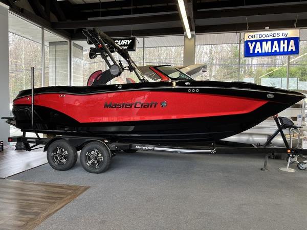 MasterCraft X22 2025 MasterCraft X22 boat in showroom, red and black design, on trailer.