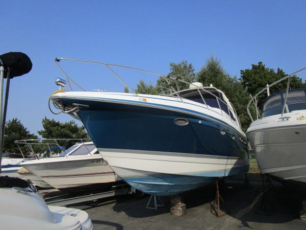 Formula 34 PC 2006 Formula 34 PC boat on dry dock, blue and white hull, surrounded by trees.