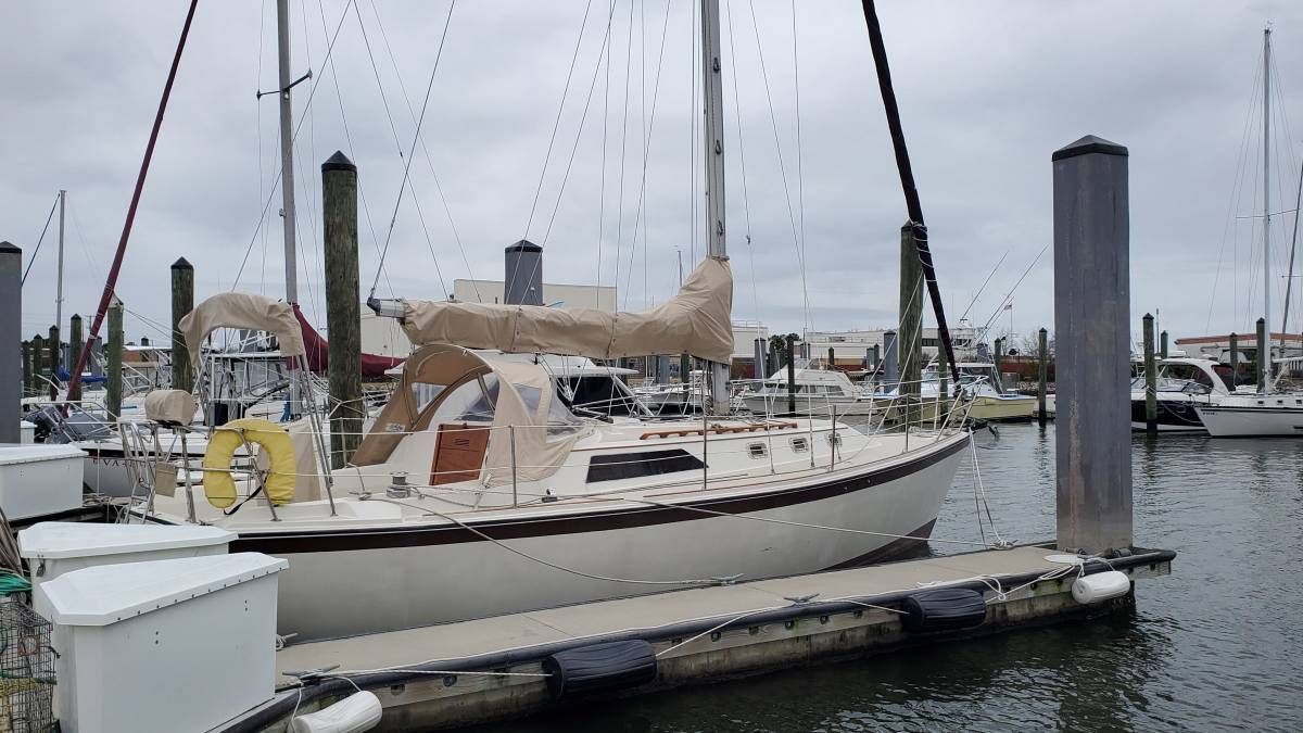 O'Day 34 1982 O'Day 34 sailboat docked at marina, overcast sky, covered sails, calm water.